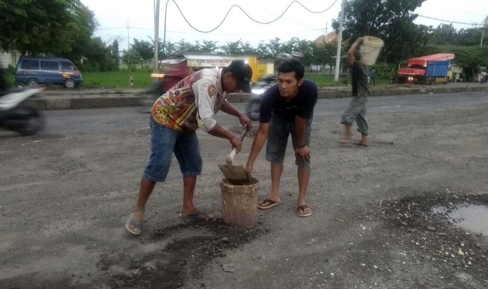 Warga menambal lubang Jalan Trans Nasional di Mojokerto
