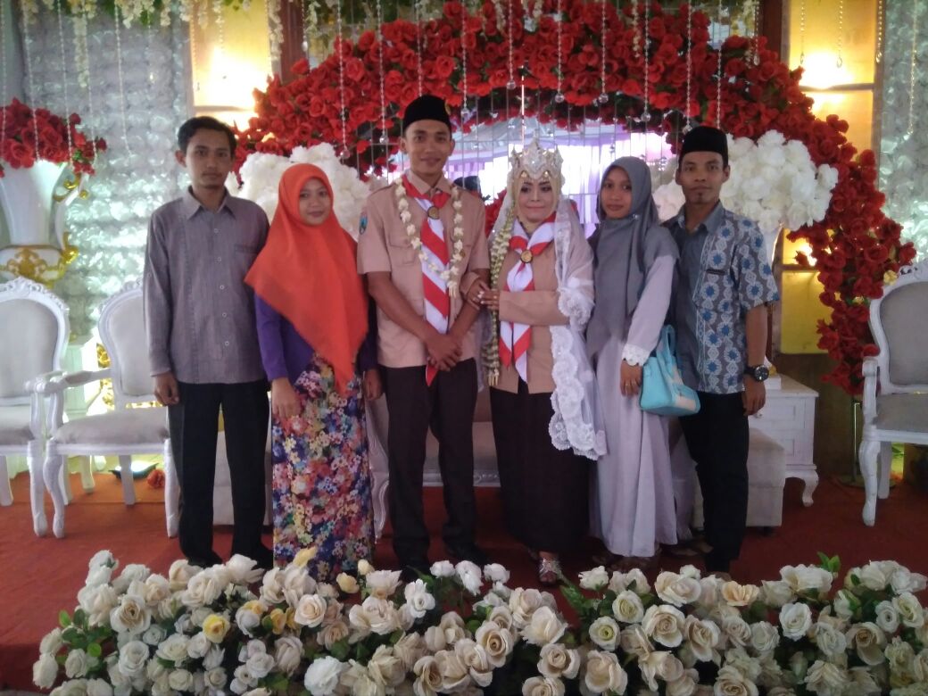 Pasangan pengantin yang mengenakan baju pramuka