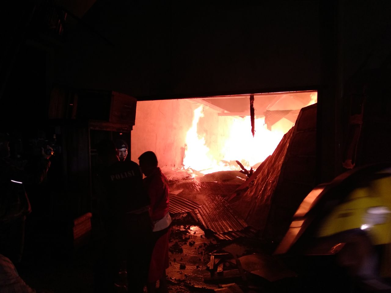 Api masih terlihat di gudang yang terbakar.