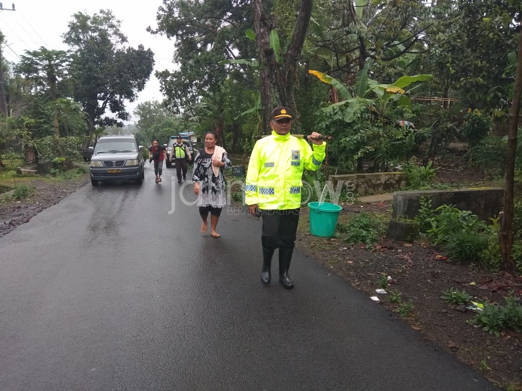 Kapolsek Songgon, AKP Bakin saat memikul timba./Foto: Irul Hamdani.