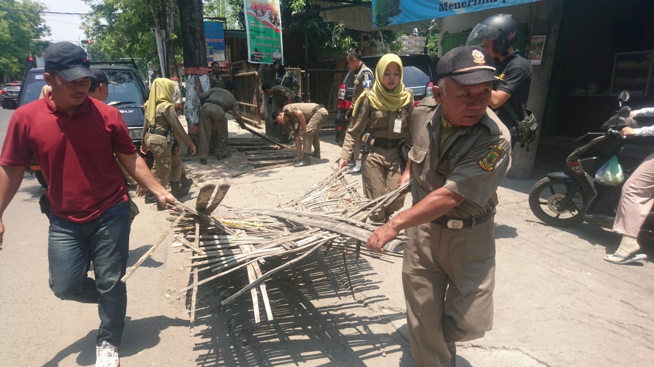 Petugas Satpol PP Kota Mojokerto saat membongkar lapak di atas saluran air./ Foto: Khilmi Sabikhisma Jane.