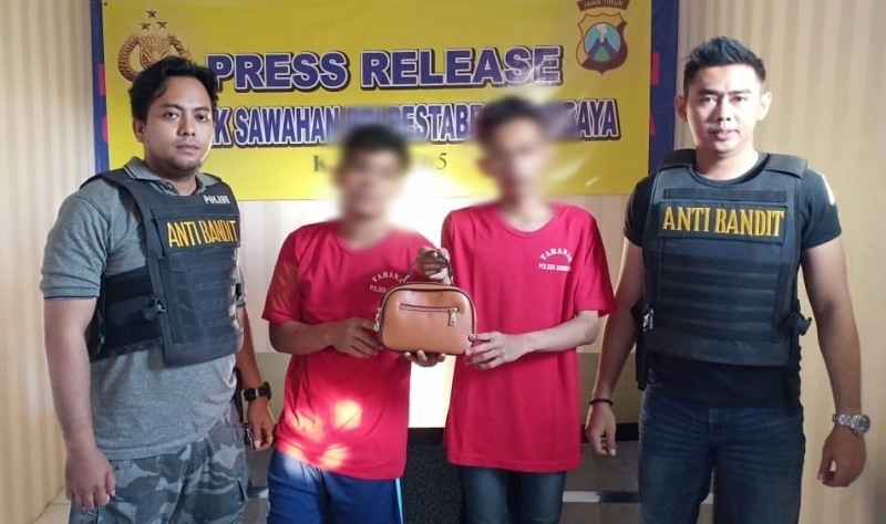 Dua pelaku (tengah) bersama tas yang mereka rampas saat beraksi. 
