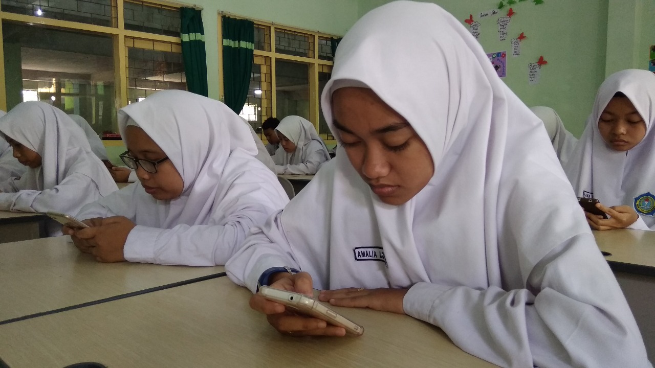 Para siswa  sedang ujian menggunakan HP berbasis android.