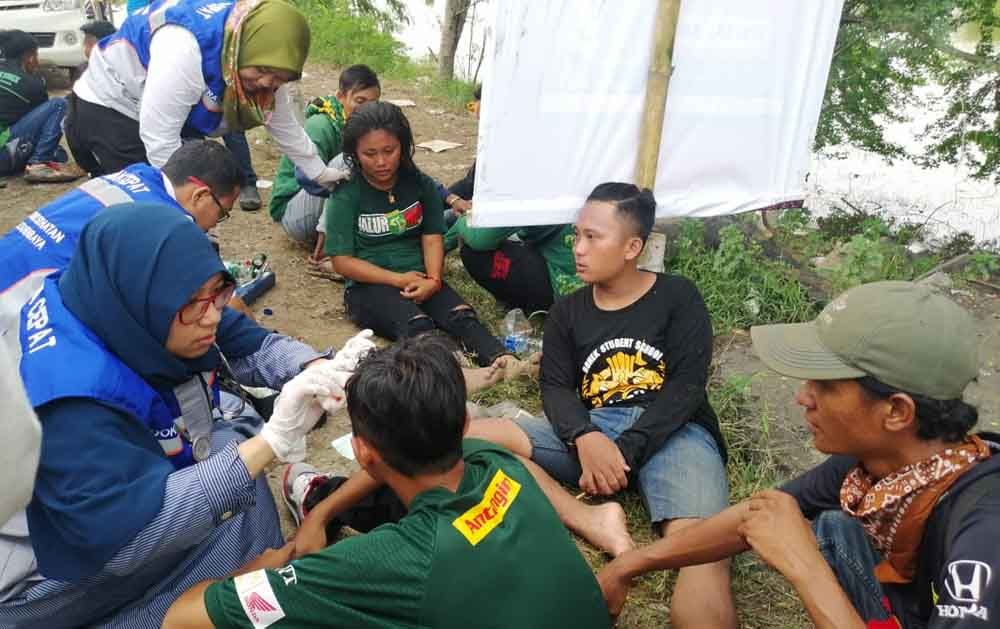 Petugas membantu suporter yang terkena lemparan batu