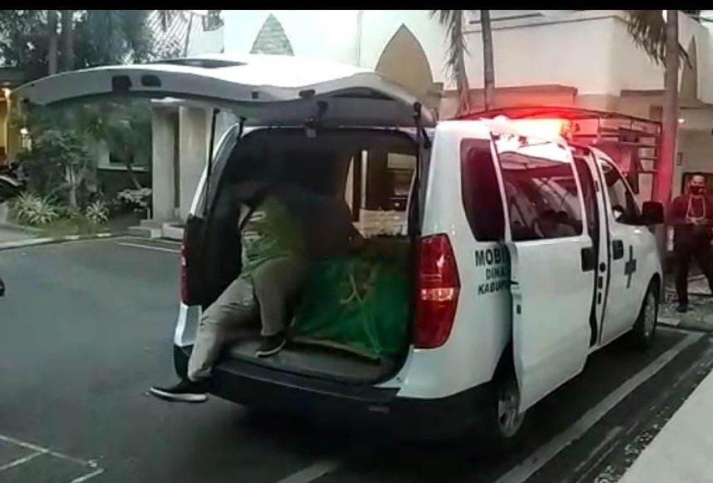 Pria berkaus lengan panjang warna hijau keluar dari ambulans