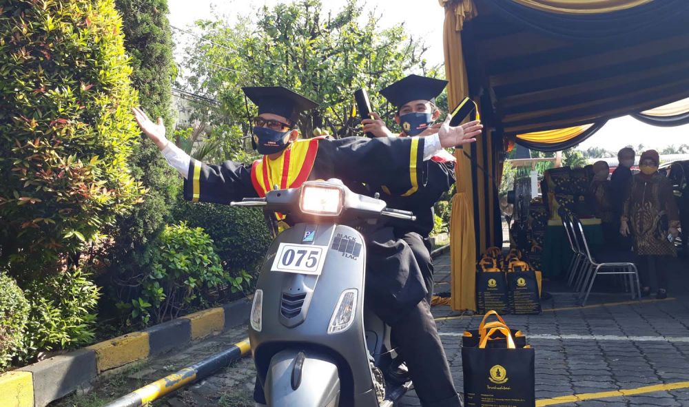 Dua wisudawan tampak gembira mengikuti wisuda drive thru di UWK Surabaya