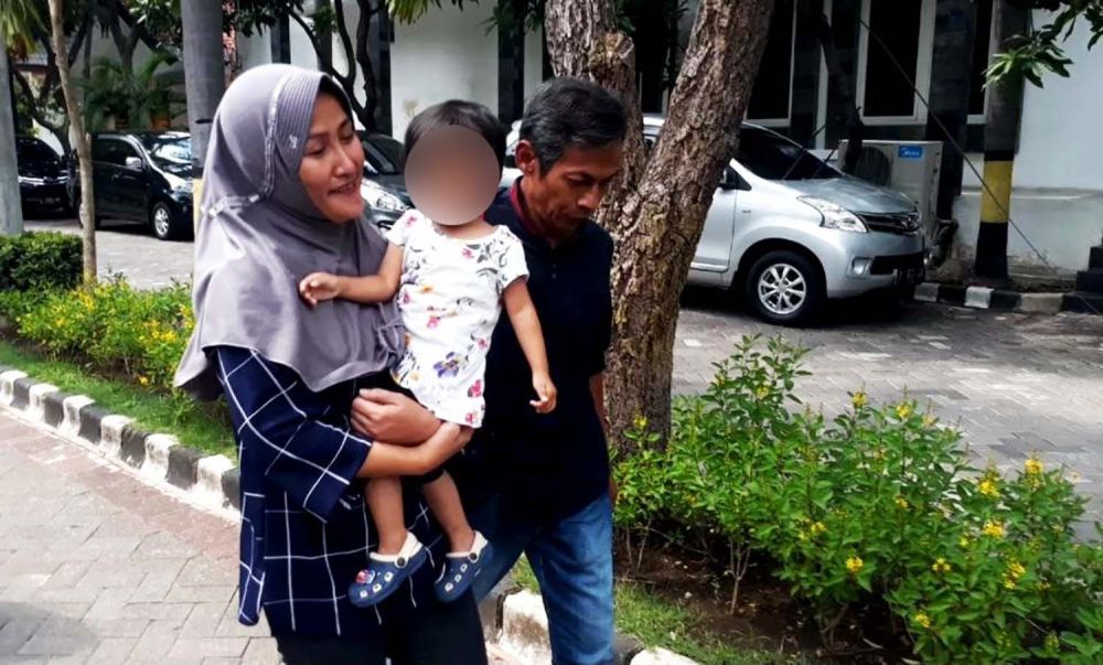 Zikria tampak gembira sambil menggedong anaknya didampingi Daru Asmara Jaya. suaminya saat keluar meninggalkan Mapolrestabes Surabaya (Foto: Zain Ahmad/jatimnow.com)