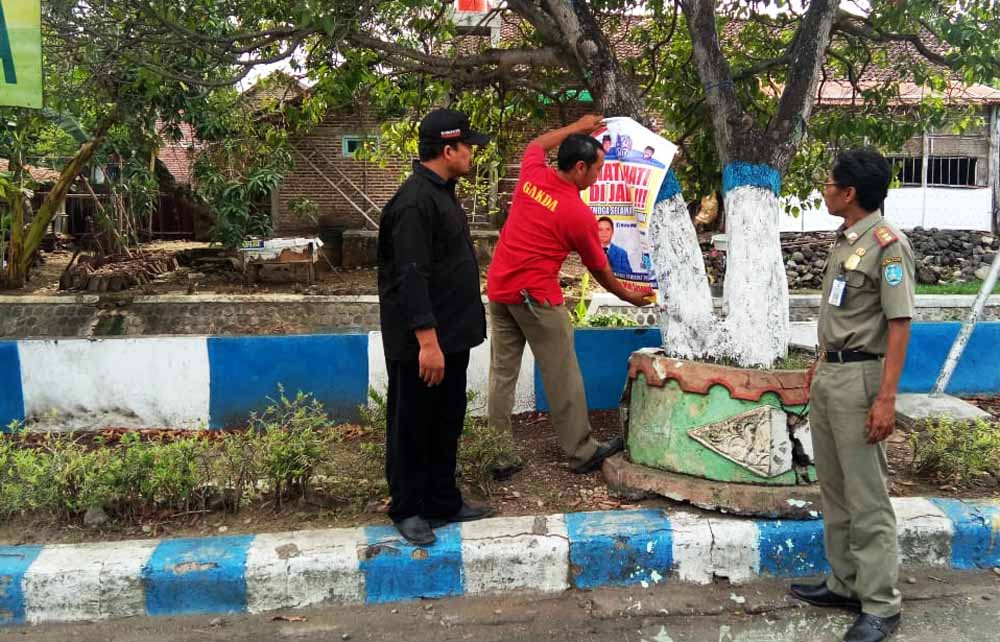 Penertiban salah satu APK yang dipaku di pohon