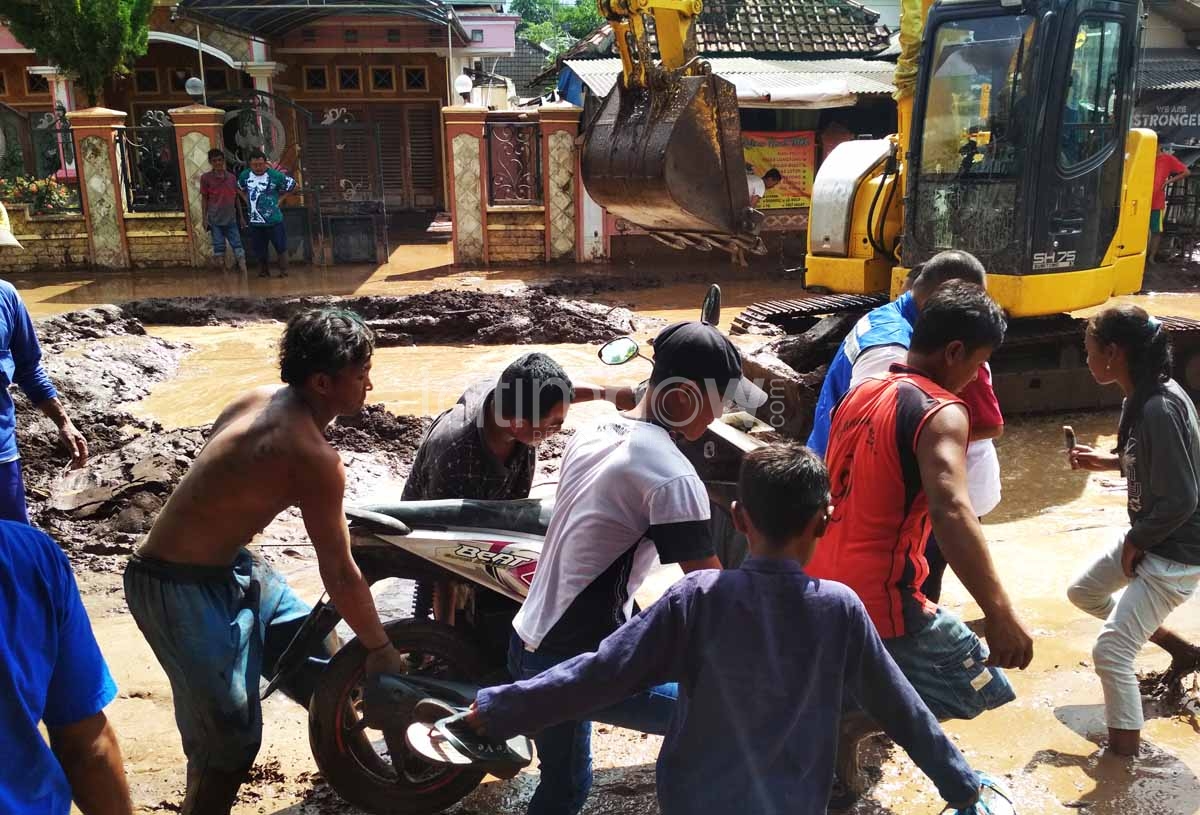 Warga bahu-membahu mengevakuasi motor yang terjebak lumpur akibat banjir bandang di Banyuwangi