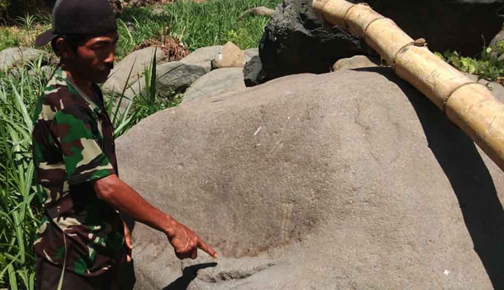 Seorang warga menunjukkan lafaz Allah pada batu kali