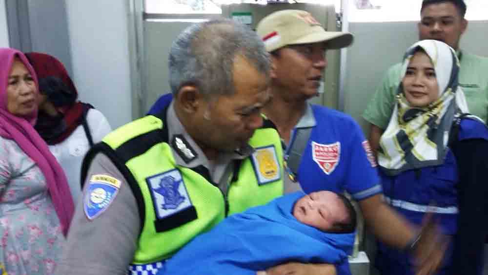 Petugas polisi  menggendong bayi yang ditinggalkan dalam kardus
