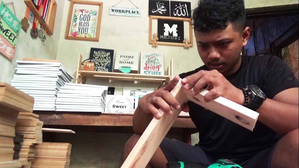 Rapid sedang mengerjakan ornamen hiasan berbahan kayu bekas