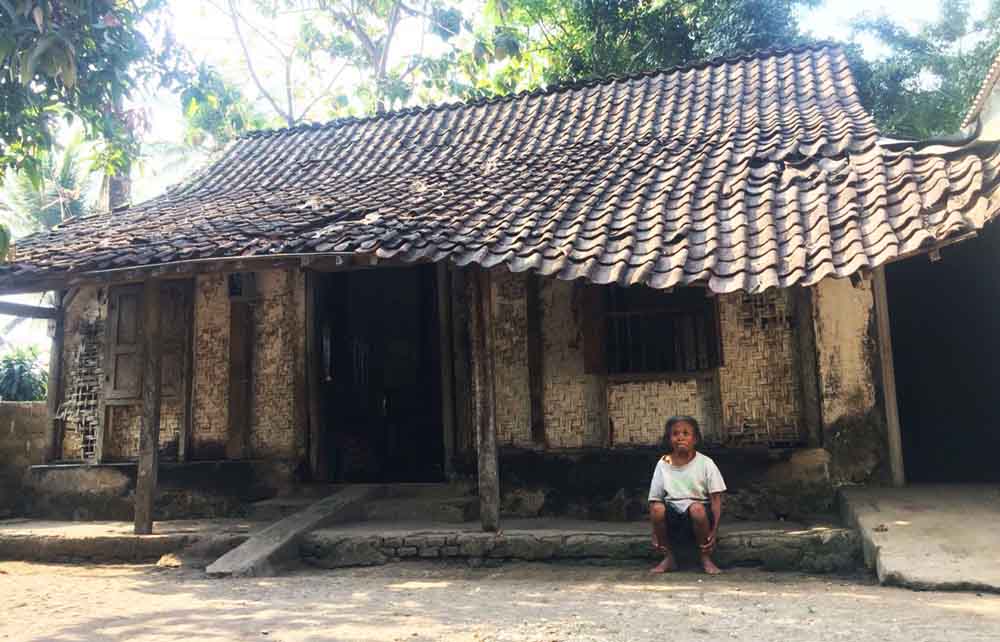 Sri Utami, istri Saji duduk di depan rumahnya