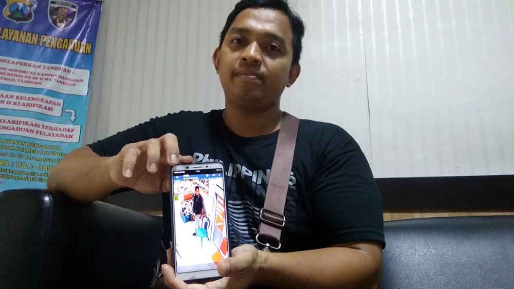 Baskoro menunjukan foto pelaku pengambil handphone