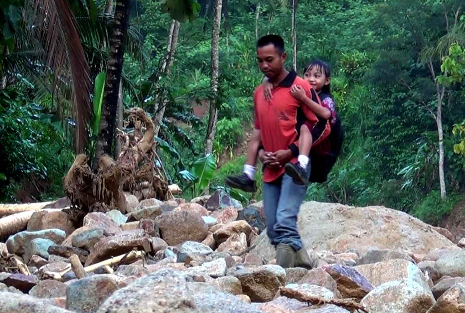 Seorang warga Pacitan menggendong anaknya menuju ke sekolah.