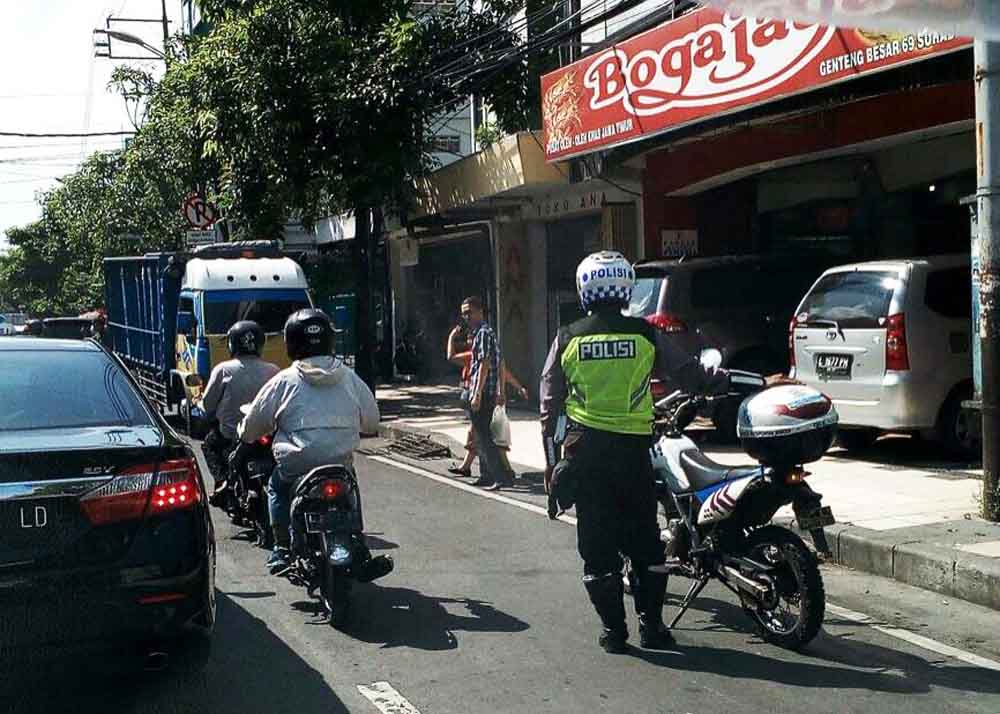 Petugas Polisi Aiptu Antasari tengah menghadang truk lawan arus di Jalan Genteng Surabaya.