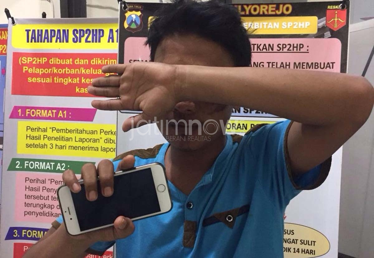 Fathur Rohman bersama HP yang dirampasnya saat diamankan di Mapolsek Mulyorejo Surabaya.