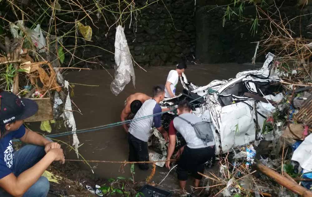 Warga mengevakuasi mobil Honda Jazz yang ringsek akibat terseret air saat hujan deras mengguyur Kota Malang