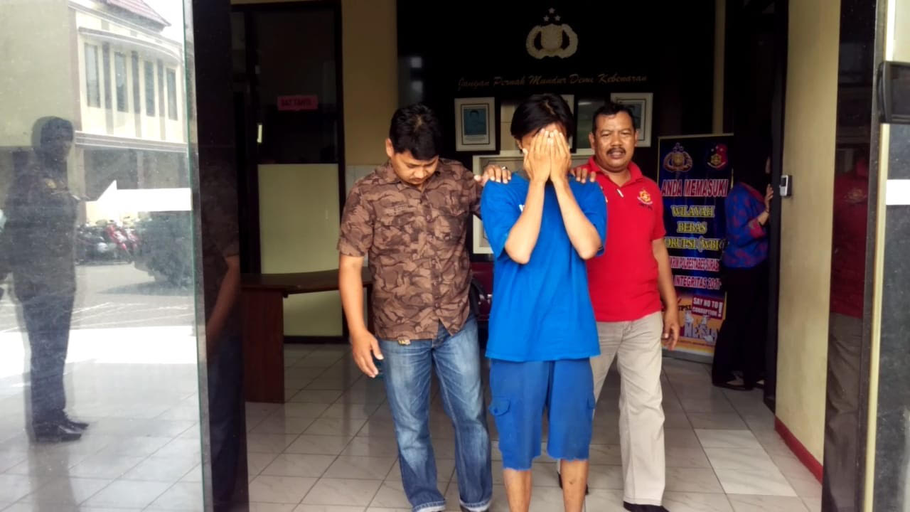 Deni (menutup wajah) saat di Mapolrestabes Surabaya.