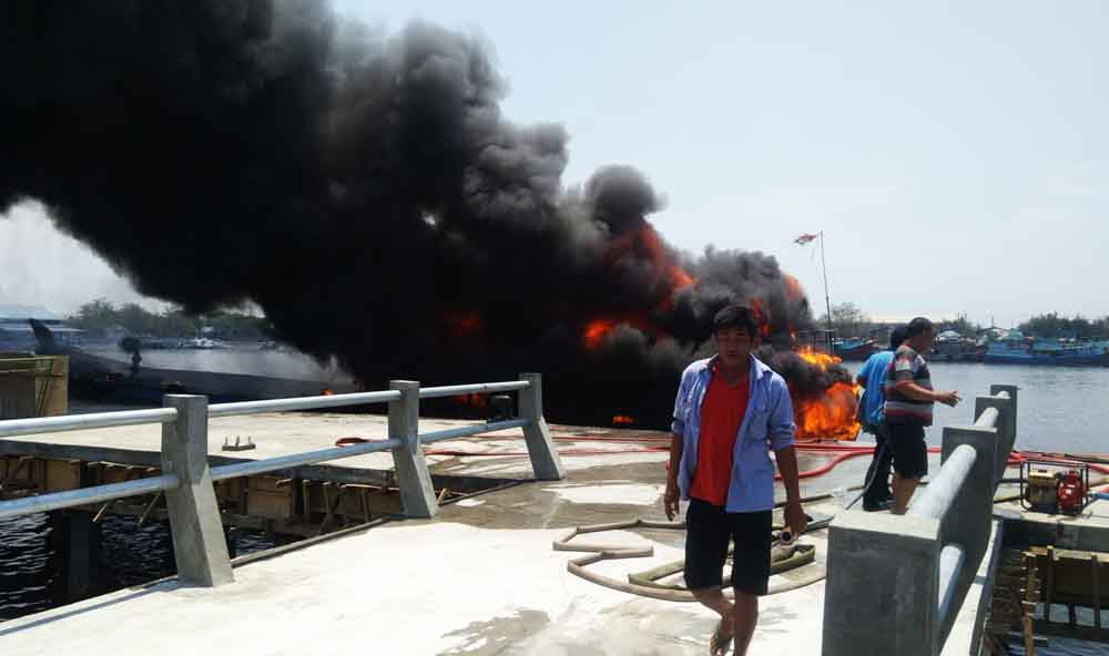 Warga berupaya memadamkan kobaran api kapal terbakar