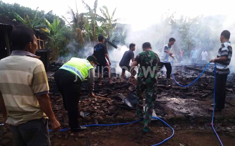 Warga bersama petugas berupaya memadamkan api di rumah milik Sukisman