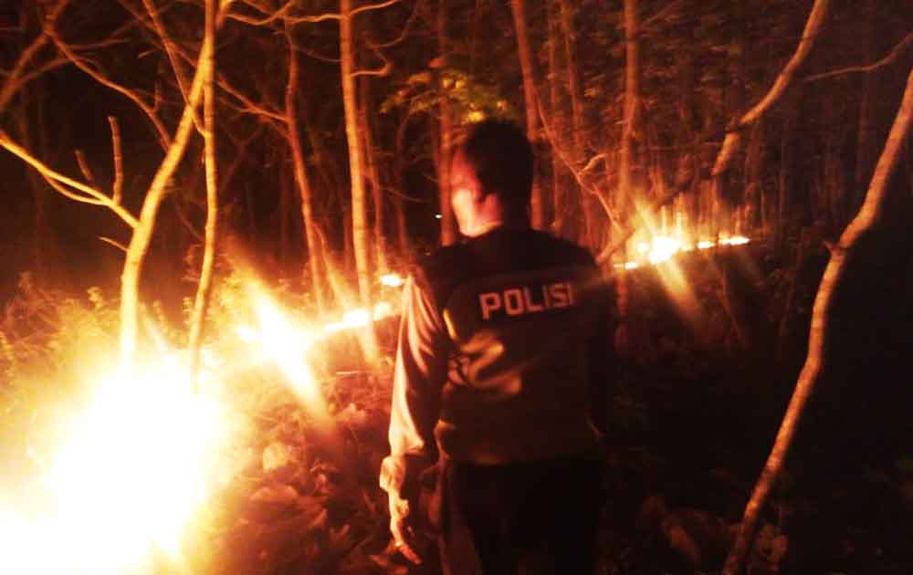 Petugas kepolisian terlihat berupaya memadamkan api