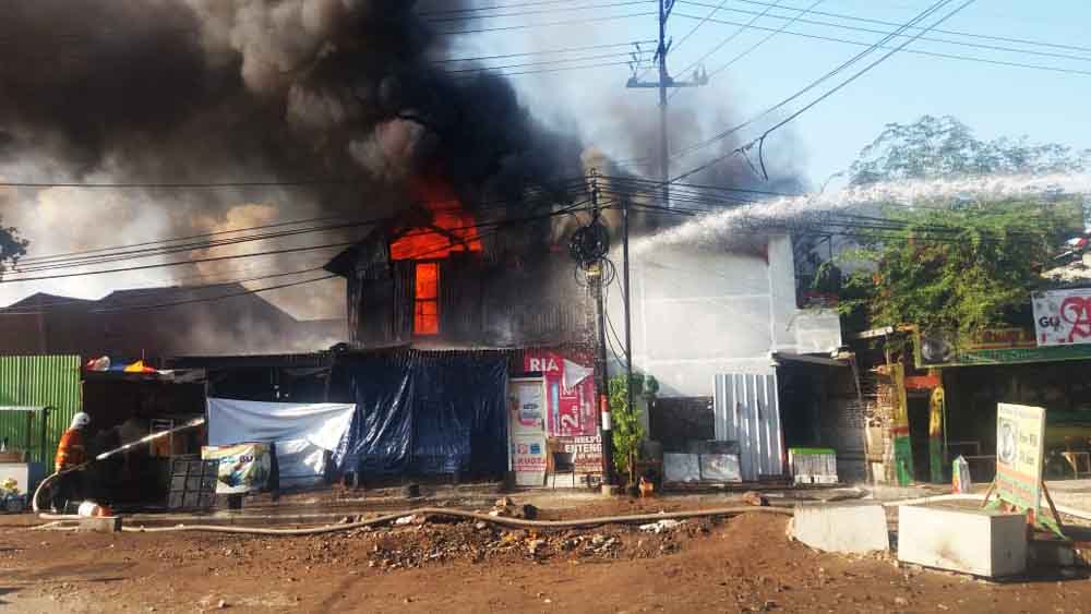 Petugas berupaya memadamkan kobaran api dari rumah terbakar