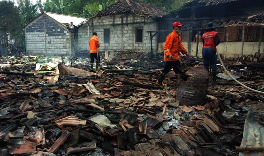 Petugas  melakukan pembasahan dua rumah yang terbakar di Mojokerto