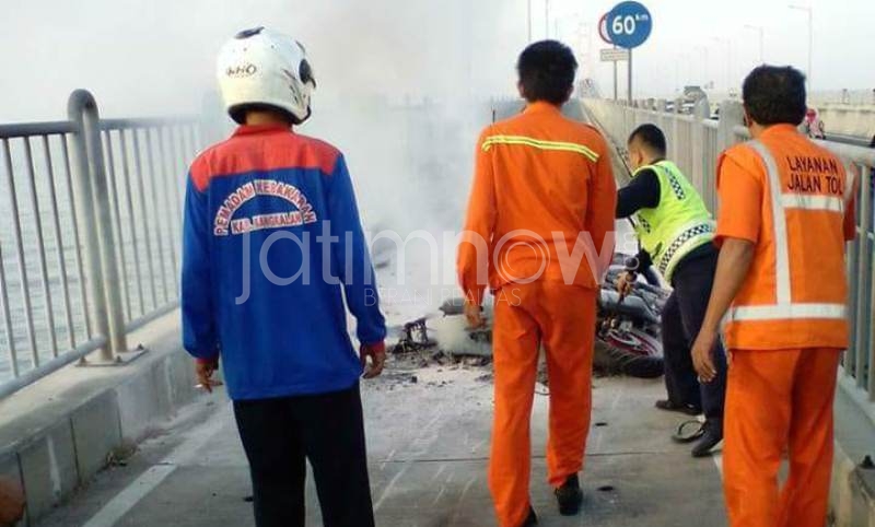 Petugas melakukan pembasahan ke sepeda motor yang terbakar di Jembatan Suramadu/Foto: Istimewa