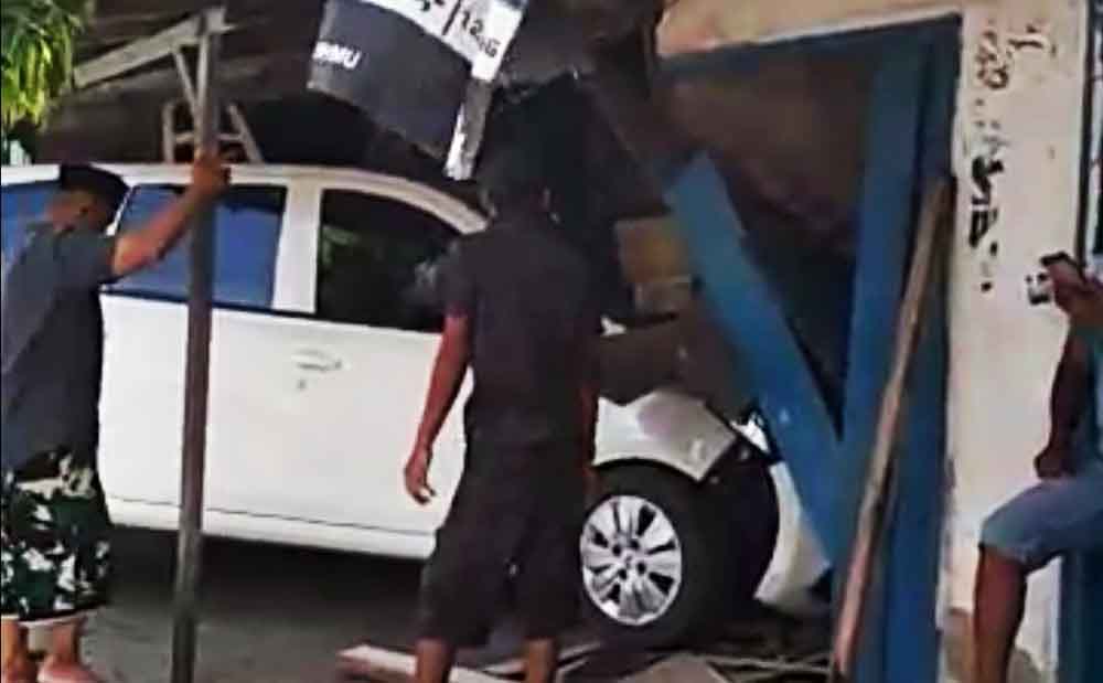 Warga berupaya mengeluarkan mobil yang menabrak warung
