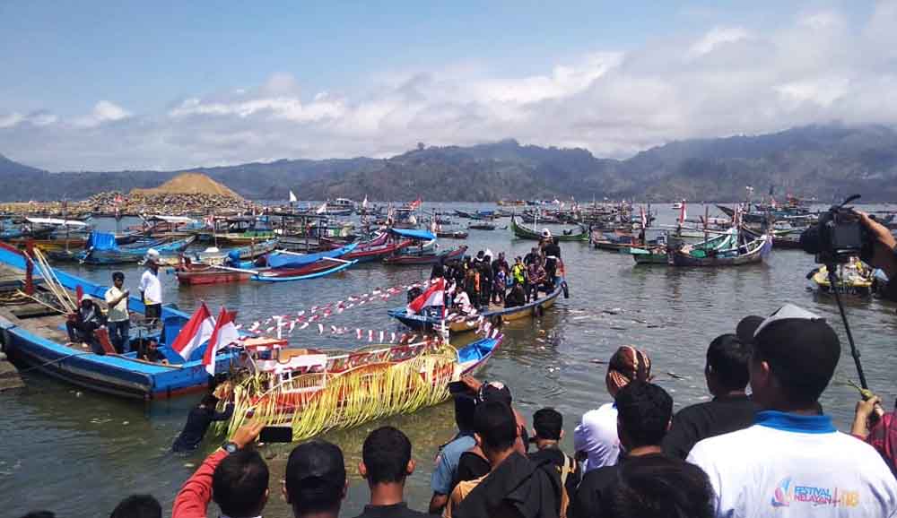 Proses pelarungan sesaji dan makanan yang dianikan perahu kecil

