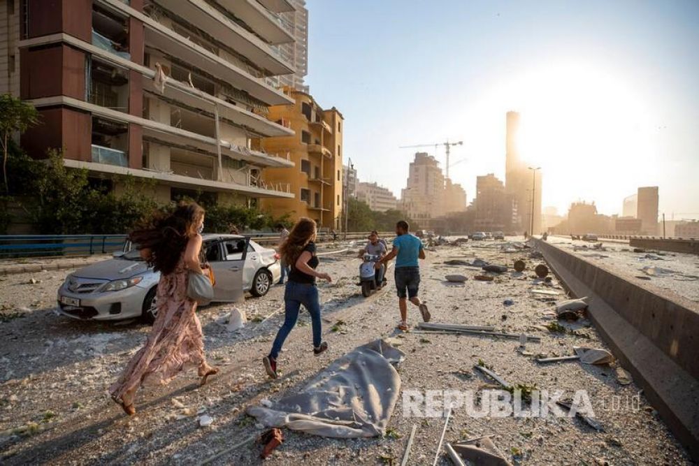 Warga berlarian dari lokasi ledakan di pelabuhan Beirut, Lebanon, Selasa (4/8) waktu setempat (Foto: AP/Hassan Ammar)
