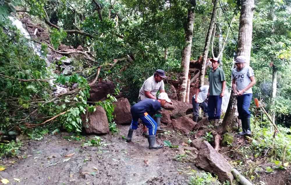 Warga membersihkan longsoran tebing yang menutp akses dua kampung