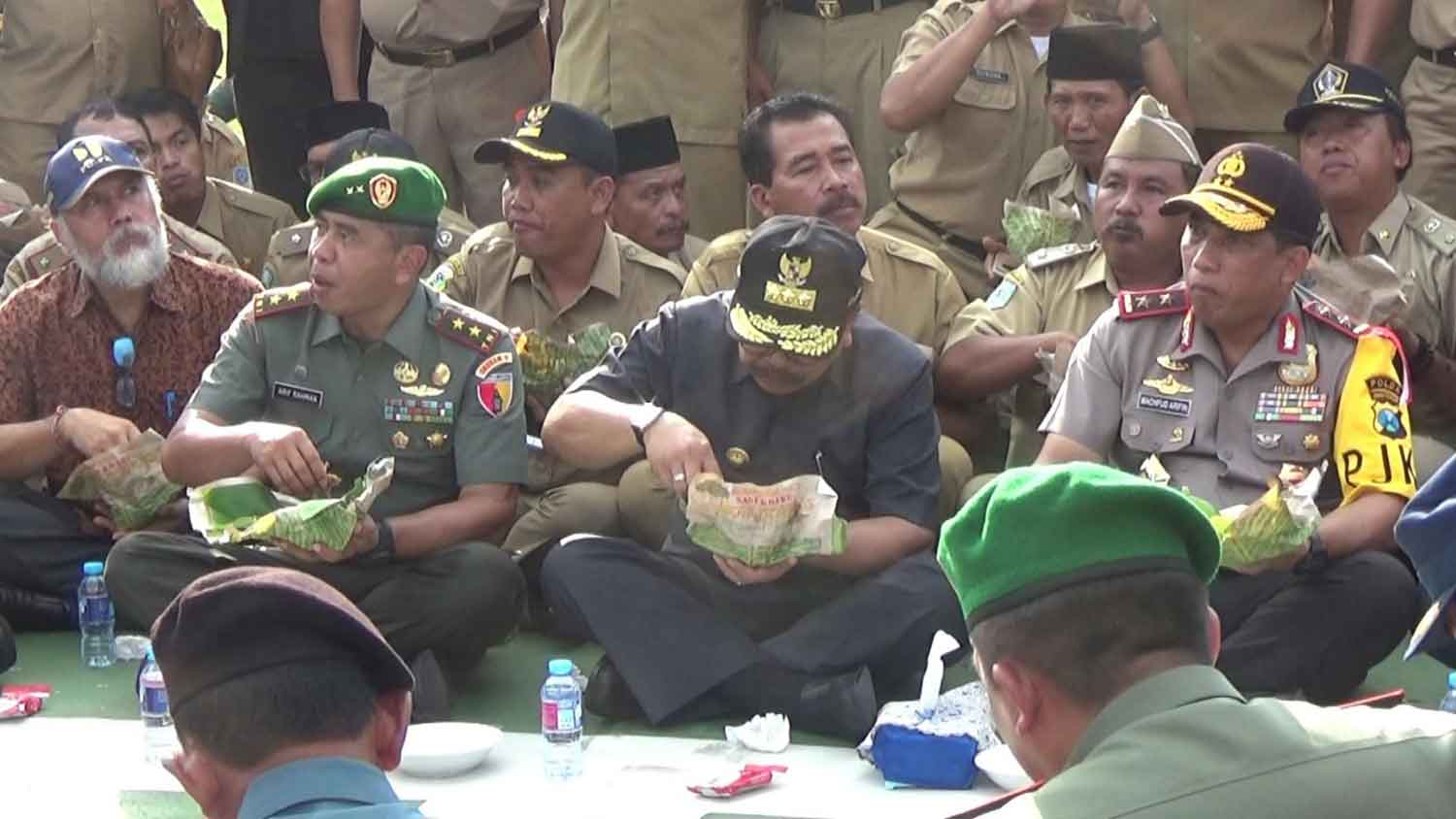 Kapolda Jatim, Gubernur dan Kepala Staf Gartap Surabaya, menikmati nasi bungkus dengan lesehan di lapangan.