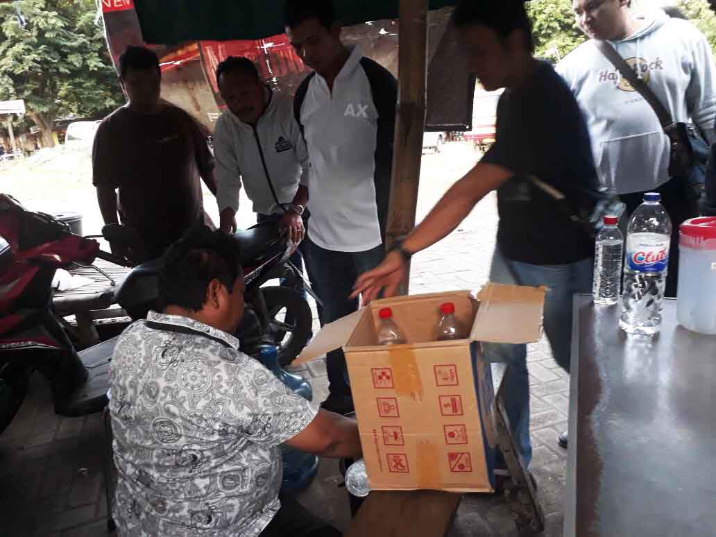 Salah satu pengedar miras (duduk), saat diberantas oleh Satreskrim Polrestabes Surabaya.

