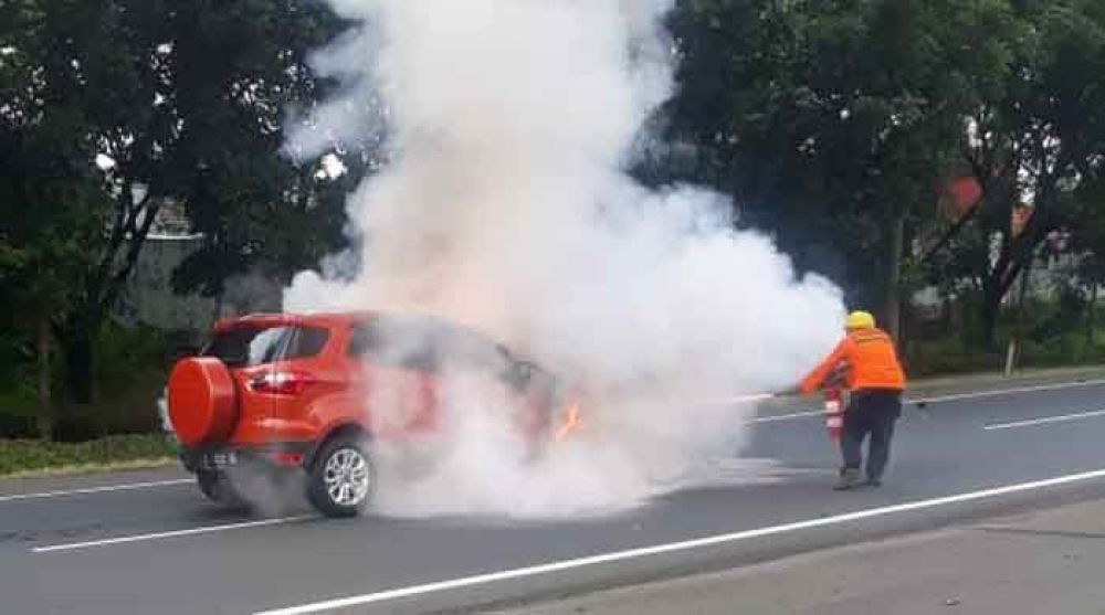 Petugas PMK berusaha memadamkan api yang membakar mobil Ford