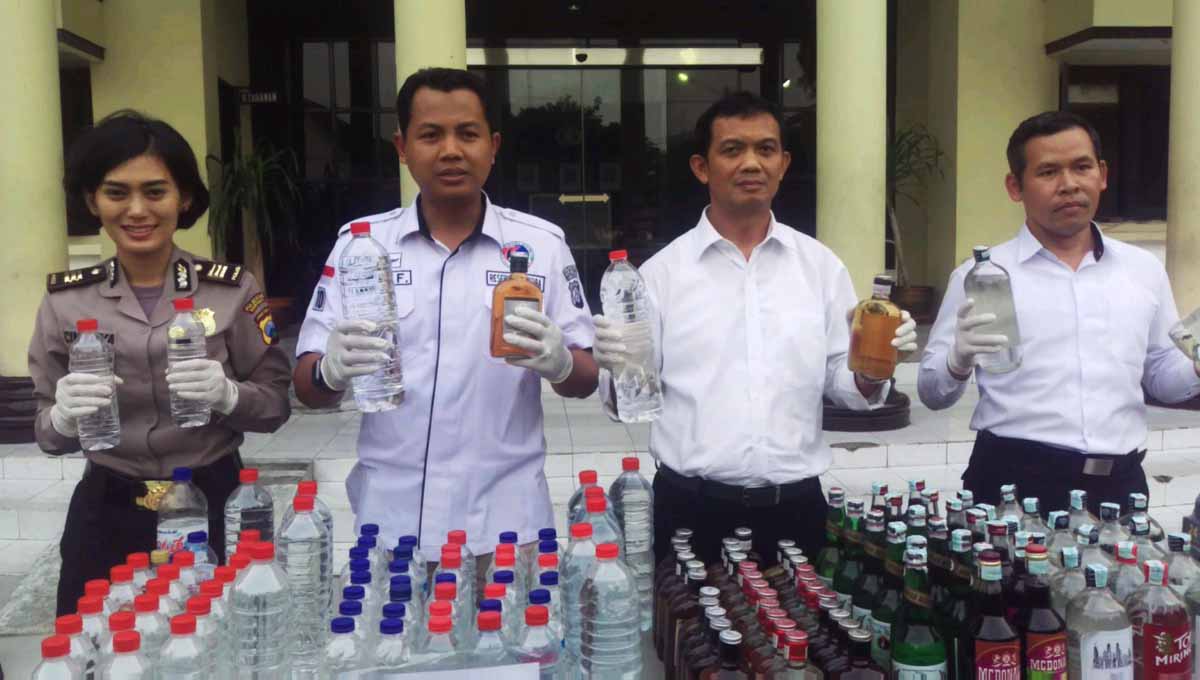 Petugas Polrestabes Surabaya menunjukkan hasil razia miras oplosan dan tak berizin.