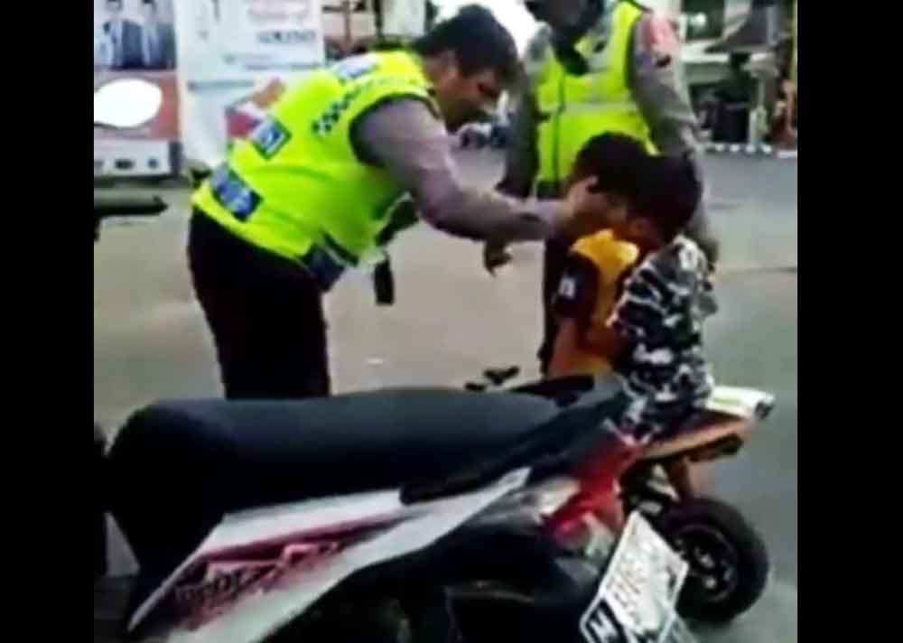 Petugas polisi sedang mendekati pemotor cilik agar tak ketakutan/Istimewa