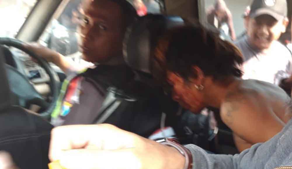 Tersangka saat diamankan oleh petugas polisi dari amukan massa