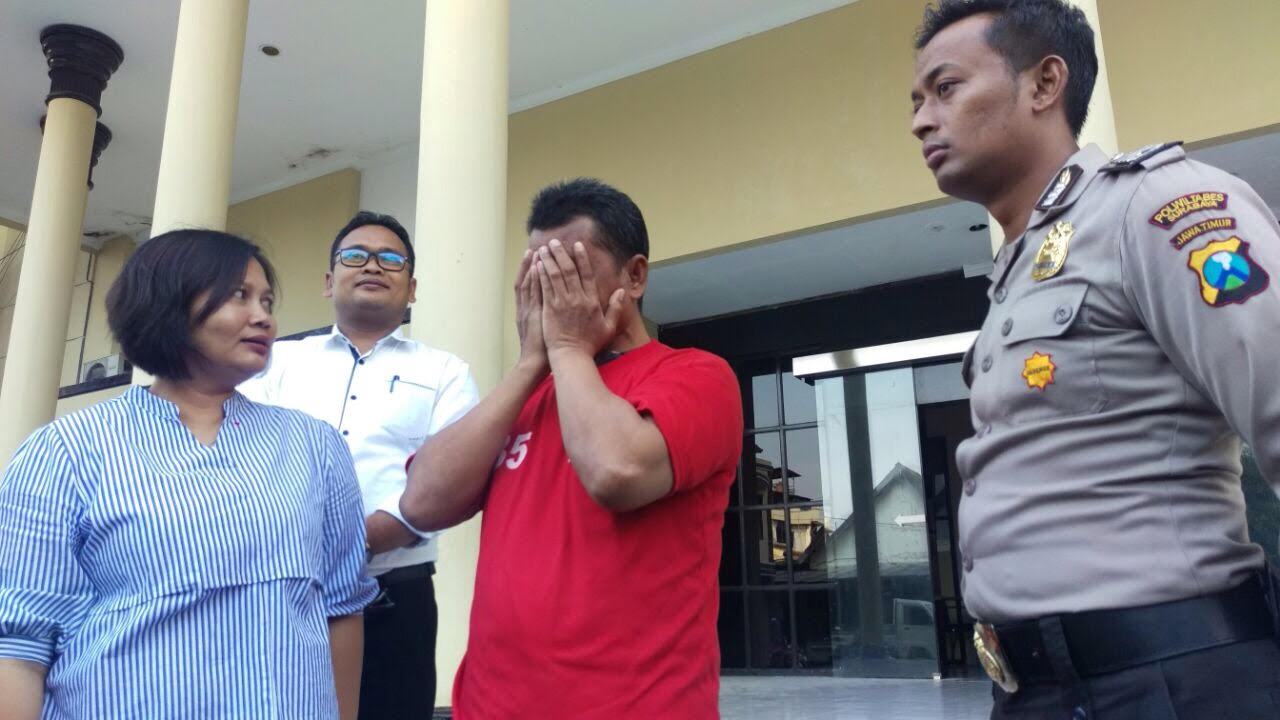Sukisno (menutup wajah) saat di Mapolrestabes Surabaya.

