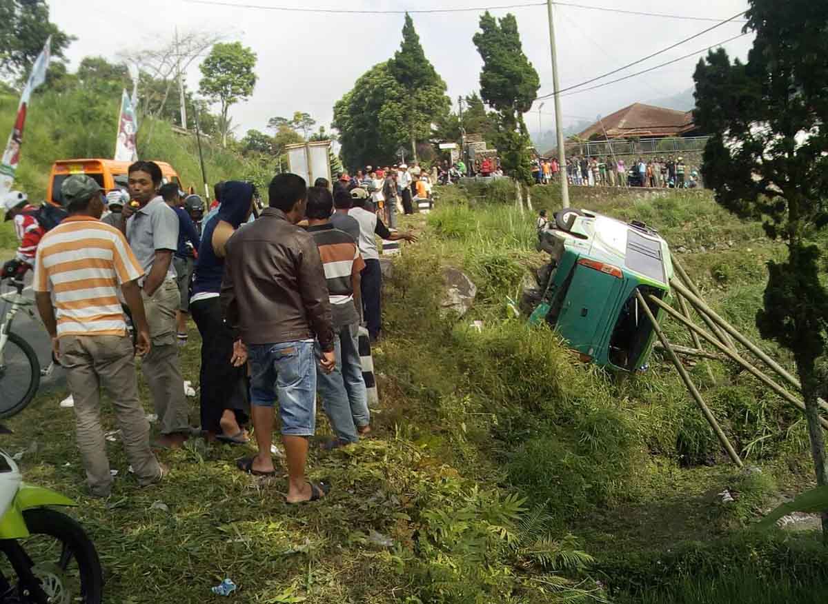 Warga nampak berupaya membantu evakuasi bus yang terguling.