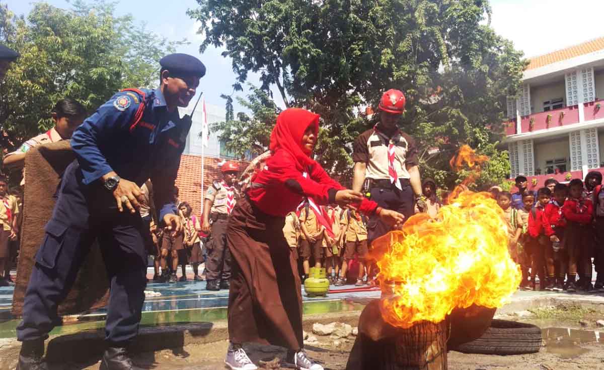 Siswa SDN Kapasari Surabaya sedang memadamkan api dari tong yang terbakar.