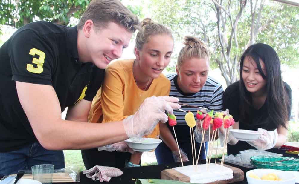 Tiga mahasiswa asing sedang membuat kue