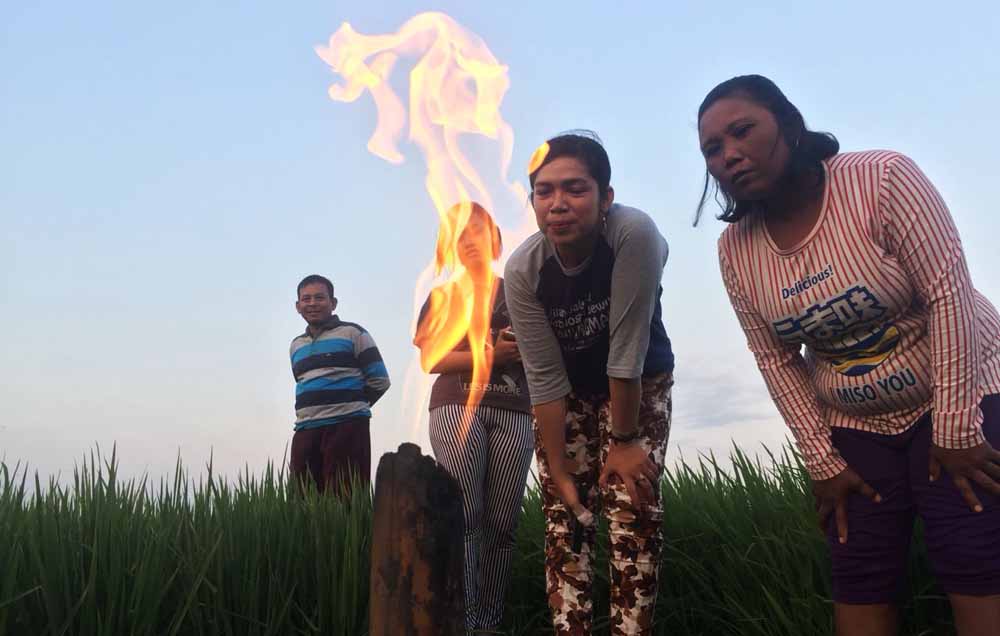 Warga melihat sumur yang mengeluarkan gas serta menyala saat disulut api