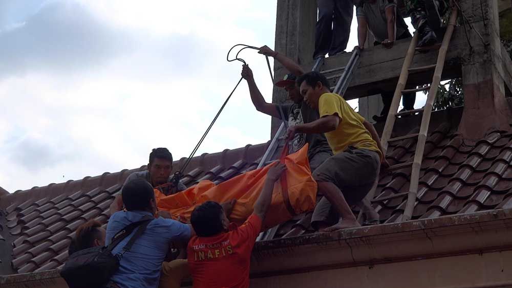 Petugas evakuasi jenasah korban yang tewas tersetrum di dalam tandon air.