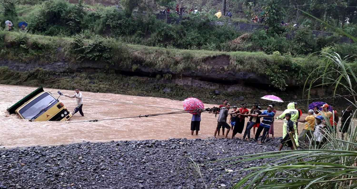 Warga dan petugas Kepolisian berusaha mengevakuasi truk pasir.