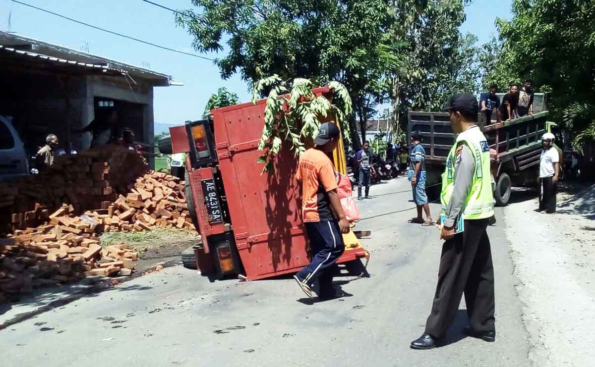 Warga berusaha mengevakuasi truk terguling di Desa Ngeraket Ponorogo.