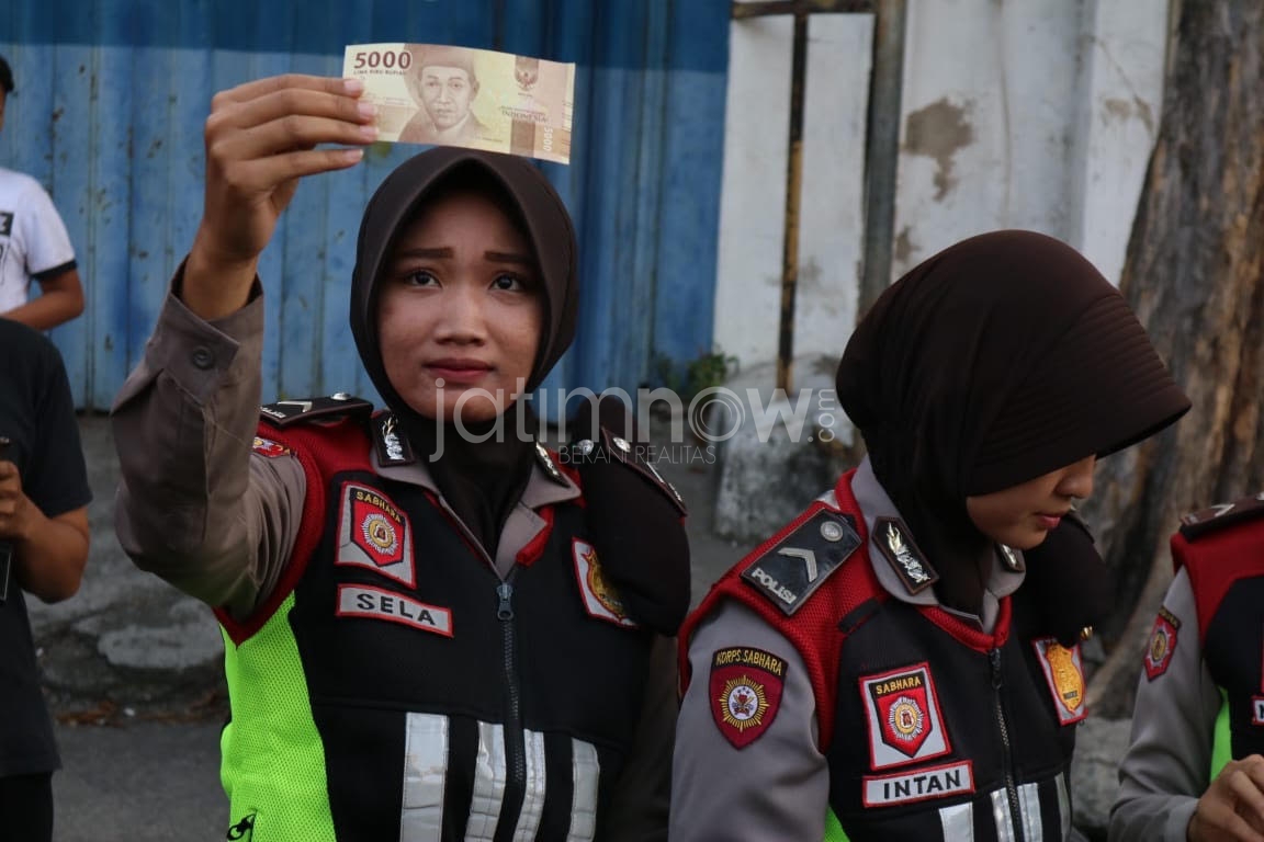 Polisi mengecek keaslian uang baru. /Foto: Narendra Bakrie.