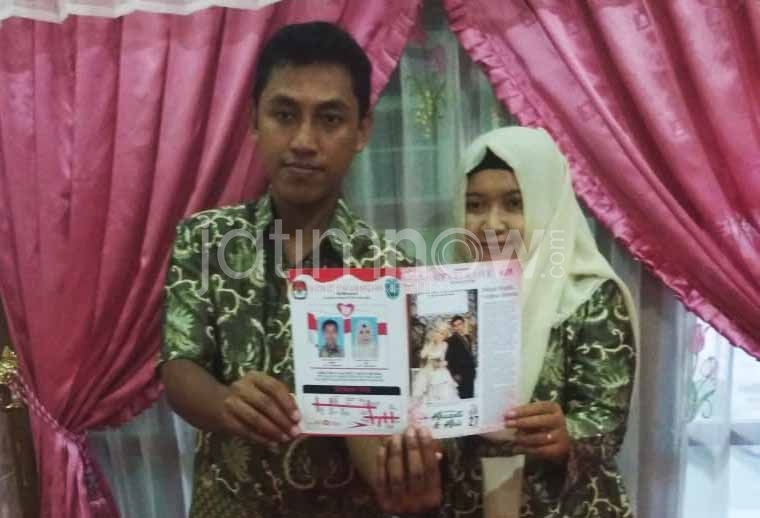 pasangan pengantin asal Ponorogo menunjukkan surat undangannya yang didesain menyerupai surat suara