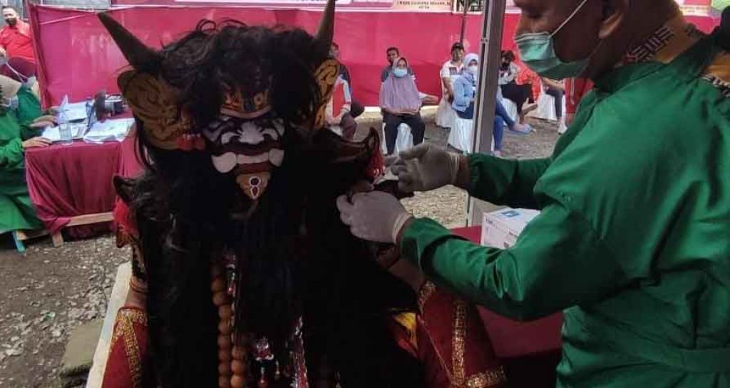 Penggiat seni dengan mengenakan busana Jaranan Buto Banyuwangi saat divaksinasi Covid-19